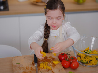 Young Girl Vlogger Making Social Media Video About Cooking At Home, looking on smartphone on tripod. episode about healthy eating. concept of attraction children to healthy diet of early age
