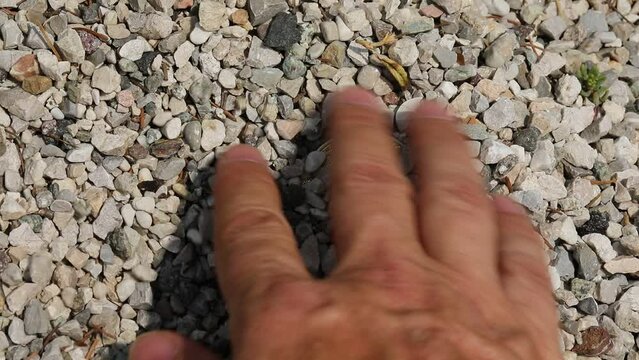 hand digging and finding two golden bitcoins in the middle of the gravel
