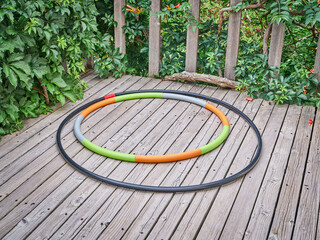 weighted hula hoop and one home made from a sprinkler pipe  on a wooden backyard deck in summer...