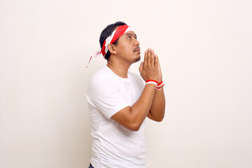 Fototapeta na wymiar Asian man standing with praying gesture for celebrating indonesian independence day.