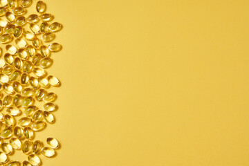 transparent capsules with omega on a yellow background on the left side of the picture. dietary supplements, vitamins. copyspace
