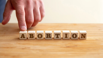 Obraz na płótnie Canvas Abortion concept. Male hand and Abortion Text on wooden blocks.