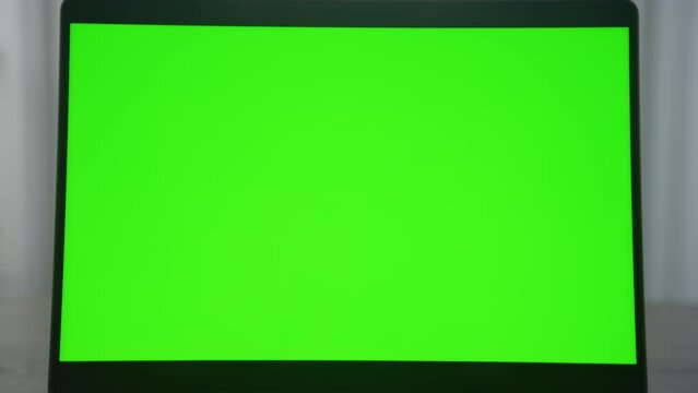 Slow optical zoom out from a laptop computer monitor with green screen chroma key