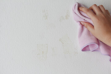 woman cleaning and remove sticky rough glue and tape remain on the old concrete wall.