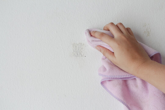 woman cleaning and remove sticky rough glue and tape remain on the old concrete wall.