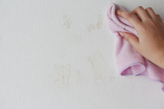woman cleaning and remove sticky rough glue and tape remain on the old concrete wall.