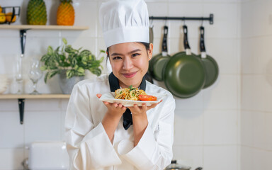 Portrait beautiful Asian professional female chef wearing white uniform, hat, showing plate of...