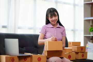 Online business owner Asian woman are using computer to check orders and customer addresses so that...
