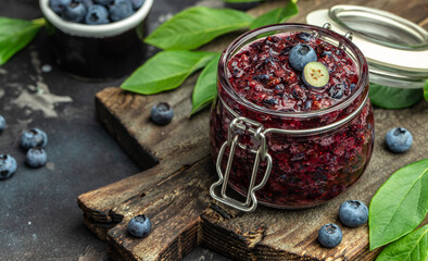 homemade blueberry jam in a jar and fresh blueberries. place for text, top view