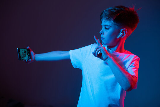 Boy taking a selfie on the phone in neon light