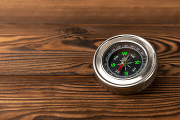 Compass on a brown wooden vintage background as a symbol of tourism. Travel concept with a compass and outdoor activities. Business and innovation concept. Copy space.