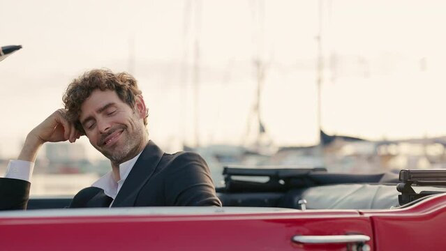 Young Man In Car. Handsome Man In Suit With Curly Hair. Girl In White Board Comes To Car And Kisses Her Man.