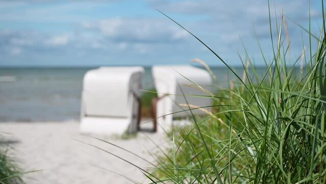 4K slow motion video of white sand and dunes grass and beach chair or strandkorb in north Germany