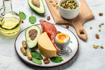 Keto diet food, salmon, avocado, cheese, egg, spinach and nuts. Ketogenic low carbs diet concept. Ingredients for healthy foods selection, place for text, top view