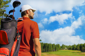 Golf player walking and carrying bag on course during summer game golfing.