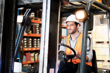 Skillful worker drives forklift in the factory .men labor worker at forklift driver position with safety suit and helmet happy smile enjoy working in industry factory logistic shipping warehouse.