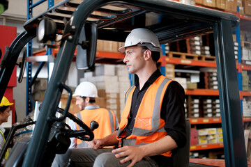 Skillful worker drives forklift in the factory .men labor worker at forklift driver position with safety suit and helmet happy smile enjoy working in industry factory logistic shipping warehouse. © Montri