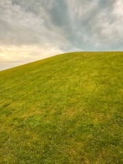 Idyllic Green Hill and Meadow Outdoor Summer Scene. Views of a fresh vivid green outdoor scene. Lush meadow of grass in the foreground. A large green hill stands tall in the background.