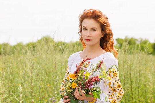 A woman in a Ukrainian costume in a field with a wild flowers