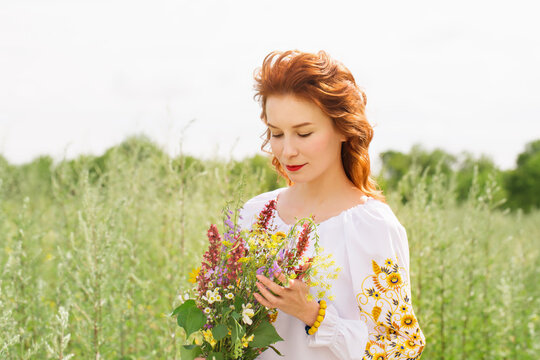 A woman in a Ukrainian costume with a bouquet of wild flowers