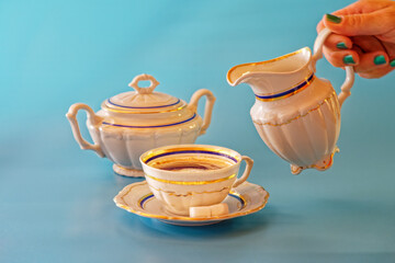 studio shot of retro wintage coffee set white with blue and gold accents on blue background