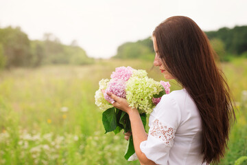 Beautiful woman with a bouquet of hydrangea in the field