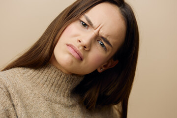 a close photo of a sad, upset young woman frowning and lowering the corners of her lips down, looking at the camera with a stern look