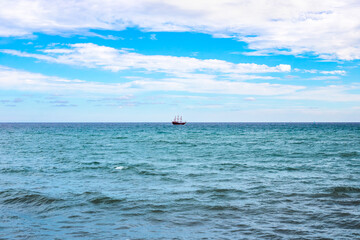 Blue Sea and sky with clouds, a sailing ship on the horizon. Seascape.