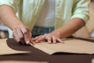 Woman marking with chalk a piece of clothing to be cut out in a sewing workshop