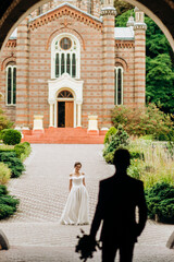 The groom steps to the bride standing on the square near the church