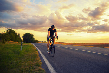 Fototapeta na wymiar Young sports man cycling with bicycle on the road in summer