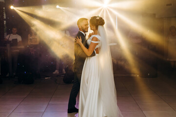 The first wedding dance of the newlyweds..Romantic atmosphere. Light floodlights in the hall.