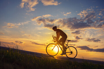 Young sports man cycling with bicycle on the road in summer - 519003871