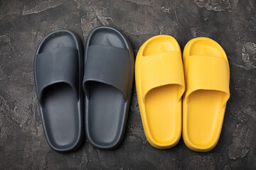 A pair of stylish rubber slippers on a black marble background.Changeable shoes.Beach shoes.Copy space. Place for text.