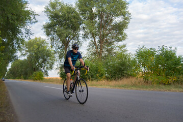 Fototapeta premium Young sports man cycling with bicycle on the road in summer