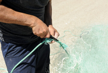 Marinero preparando las redes de pesca en el puerto pesquero de Rota, costa de Cádiz, España