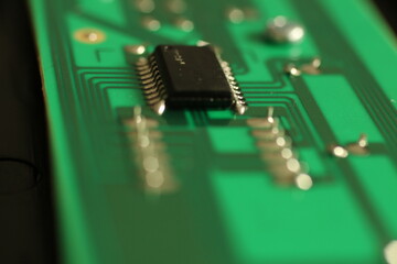 Close up of an electronic component on a green circuit board with deep bokeh