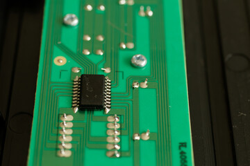 Close up of an electronic component on a green circuit board with deep bokeh
