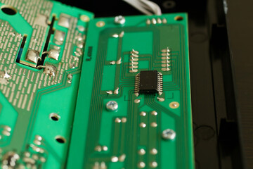 Close up of an electronic component on a green circuit board with deep bokeh