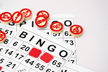 Many wooden chips with numbers and cards for a board game of bingo or lotto on a light background.