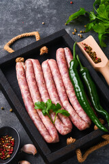 Raw sausages. Bratwurst or sausages with ingredients on cutting board with spices on a stone...