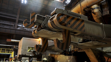 Close up for metallurgical chute at the steel factory, heavy industry concept. Giant hooks of the...