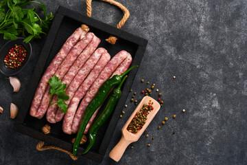 Raw sausages. Bratwurst or sausages with ingredients on cutting board with spices on a stone...