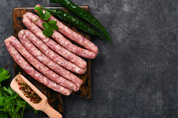 Raw sausages. Bratwurst or sausages with ingredients on cutting board with spices on a stone...