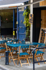 An empty outdoor area of a traditional french restaurant or cafe in a historic downtown. Tables and chairs without visitors.  Business in HoReCa. A rain droplets on table.