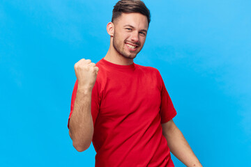 Overjoyed happy tanned handsome man in red t-shirt raise fist up have big win say Yeah posing...