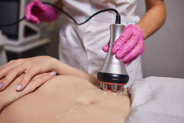 Rf skin tightening, belly. Hand of cosmetician, female body. Non surgical body sculpting.