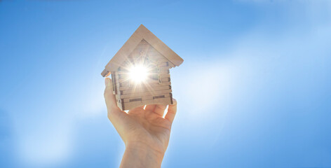 hand holding a house. House model in hand against clear blue sky