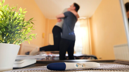 Close up of positive pregnancy test lying on a table and woman embracing a man. Stock footage....