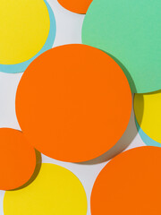 Background of yellow and orange paper circles in Memphis geometric style. Cut out circles styled layout with hard light and shadows. Vivid abstract background or template.